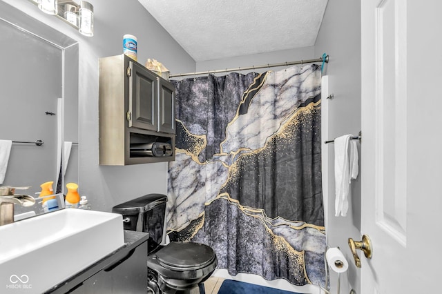 bathroom featuring toilet, sink, a shower with curtain, a textured ceiling, and tile patterned flooring