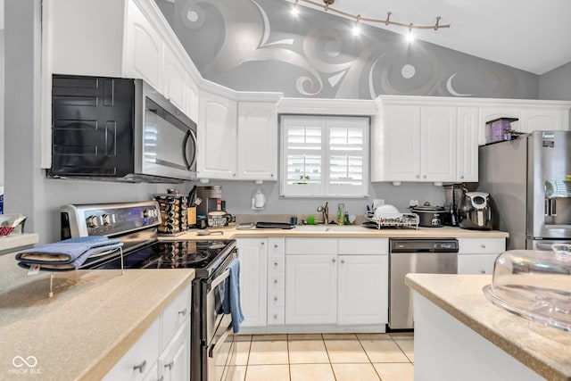 kitchen with white cabinetry, light tile patterned floors, vaulted ceiling, and appliances with stainless steel finishes