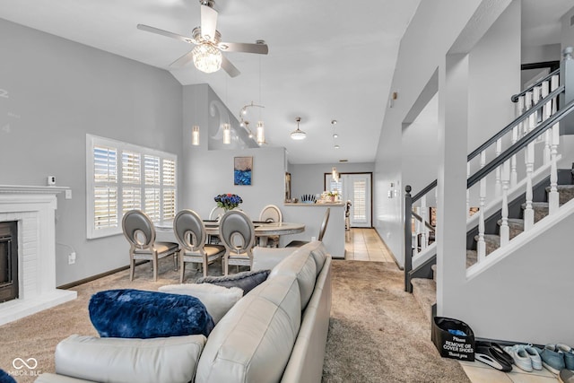 living room with a healthy amount of sunlight, a fireplace, high vaulted ceiling, and light carpet