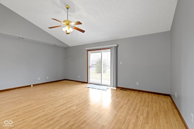 empty room featuring ceiling fan, vaulted ceiling, a textured ceiling, and light wood-type flooring