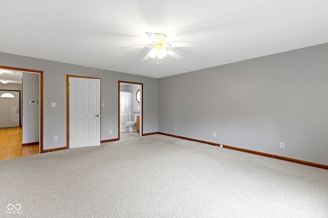 unfurnished bedroom featuring ensuite bathroom, light colored carpet, and ceiling fan