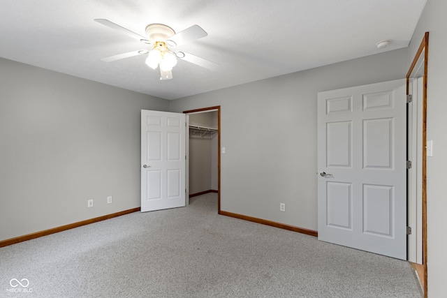 unfurnished bedroom featuring ceiling fan, a spacious closet, a closet, and carpet