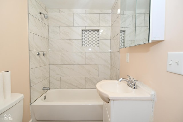 full bathroom featuring tiled shower / bath, vanity, and toilet