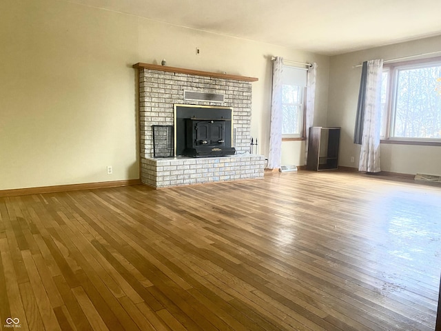 unfurnished living room with wood-type flooring and a wood stove