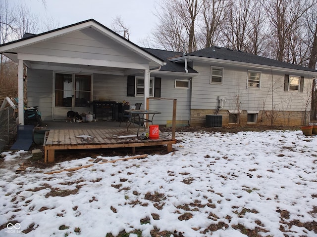 snow covered back of property with a wooden deck