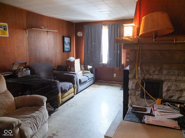 living room with a stone fireplace and wood walls