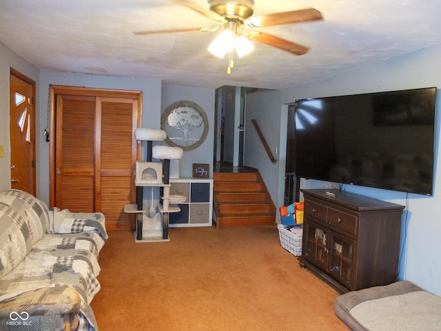 carpeted living area featuring stairs and a ceiling fan