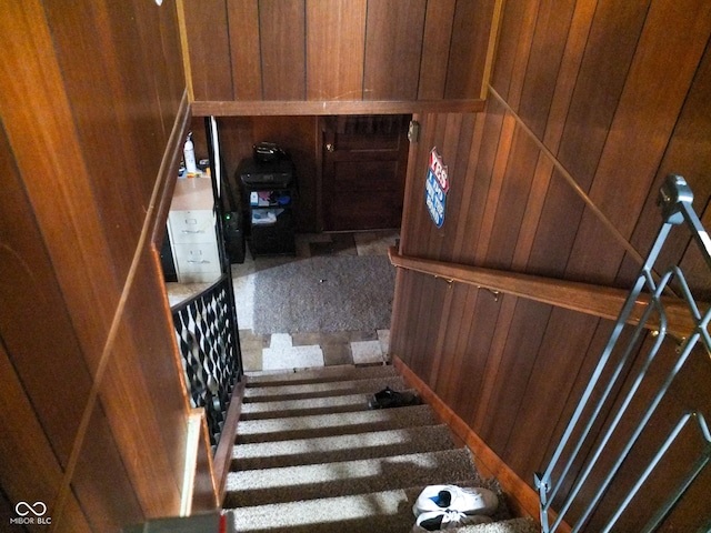 staircase featuring wood walls