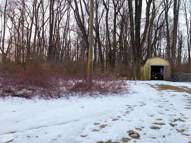 yard covered in snow with a garage, a shed, and an outbuilding