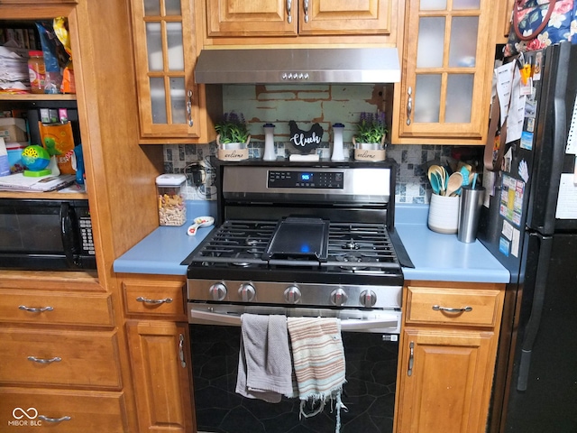 kitchen featuring tasteful backsplash, gas stove, fridge, and extractor fan