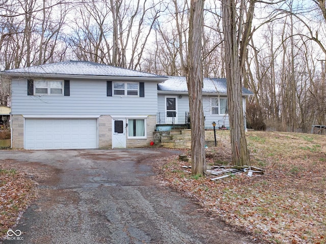 split level home with stone siding, driveway, and an attached garage