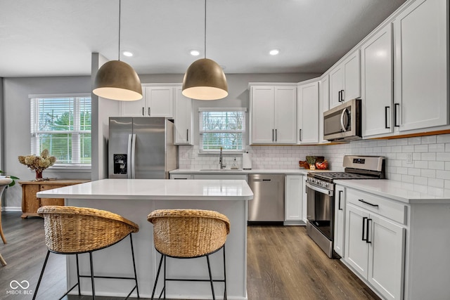 kitchen featuring pendant lighting, white cabinetry, stainless steel appliances, and a kitchen island