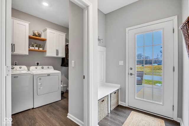 laundry room with dark hardwood / wood-style floors, washing machine and dryer, and cabinets