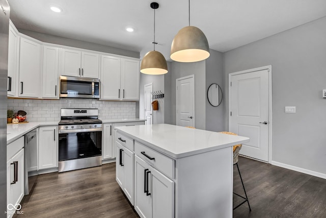 kitchen featuring white cabinetry, appliances with stainless steel finishes, decorative light fixtures, and a kitchen island