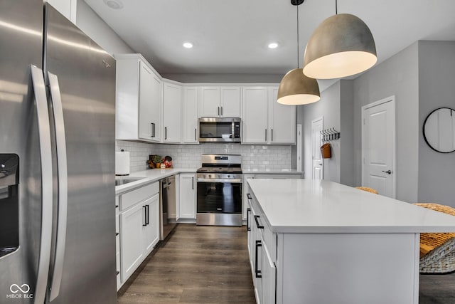 kitchen with white cabinetry, decorative light fixtures, appliances with stainless steel finishes, dark hardwood / wood-style floors, and backsplash