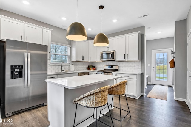 kitchen featuring pendant lighting, sink, appliances with stainless steel finishes, white cabinets, and a kitchen island