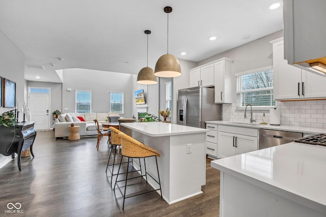 kitchen with decorative light fixtures, a center island, white cabinets, and appliances with stainless steel finishes