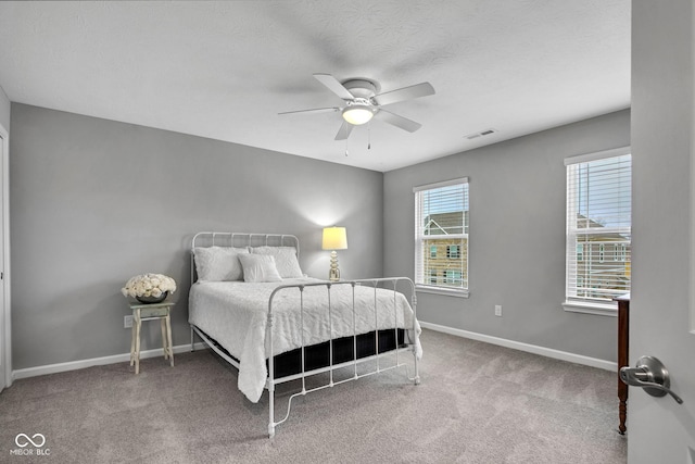 bedroom with ceiling fan, carpet, and a textured ceiling