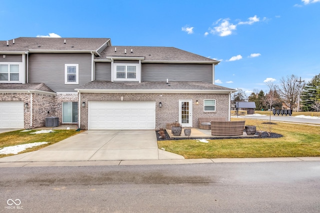 view of front of house with a garage, central AC unit, and a front lawn