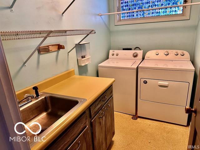 washroom featuring cabinets, washer and clothes dryer, and sink