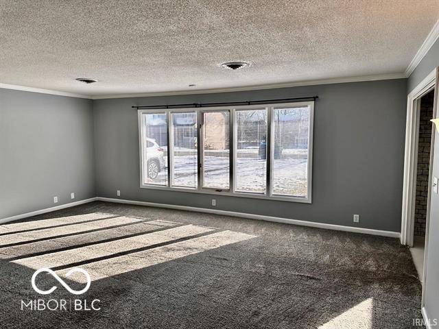 unfurnished room with dark colored carpet, a textured ceiling, and crown molding