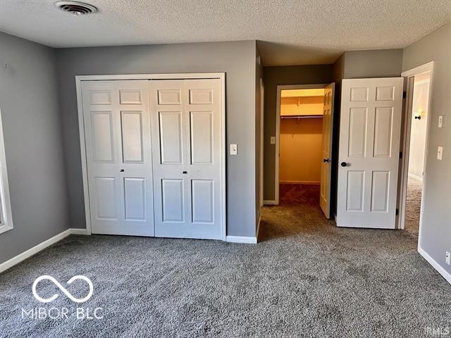 unfurnished bedroom with carpet floors, a closet, and a textured ceiling