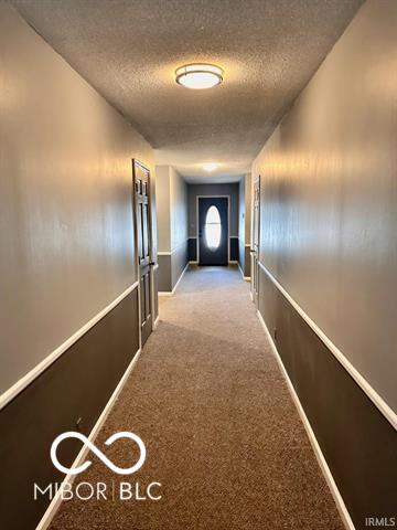 hall with a textured ceiling and carpet