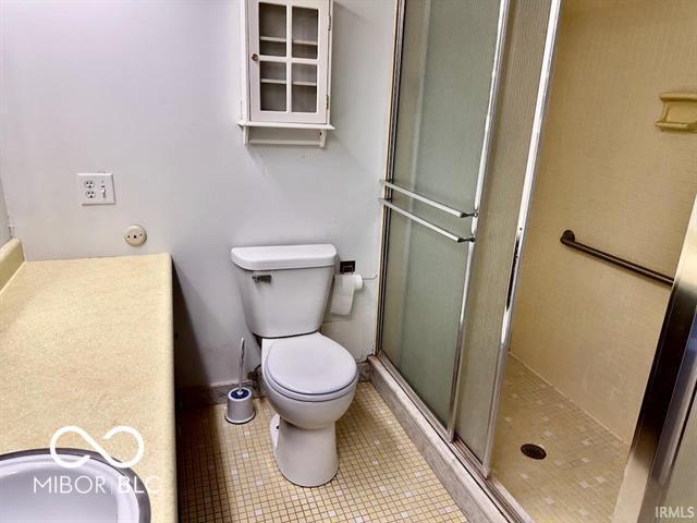 bathroom featuring an enclosed shower, tile patterned floors, and toilet