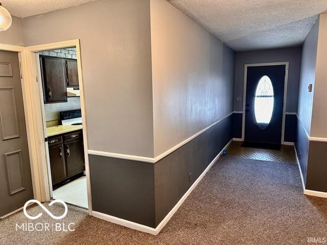 carpeted entryway with a textured ceiling