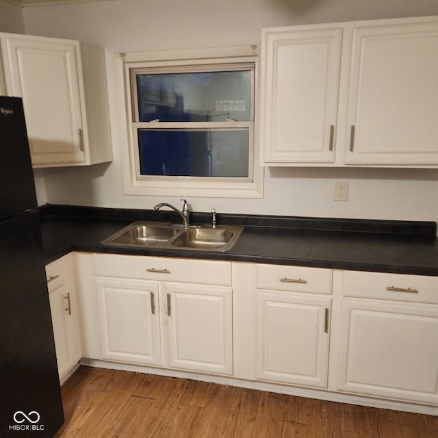 kitchen featuring sink, black refrigerator, white cabinets, and light hardwood / wood-style flooring