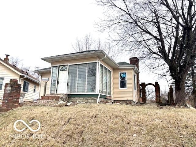 view of front of property featuring a sunroom and a front lawn