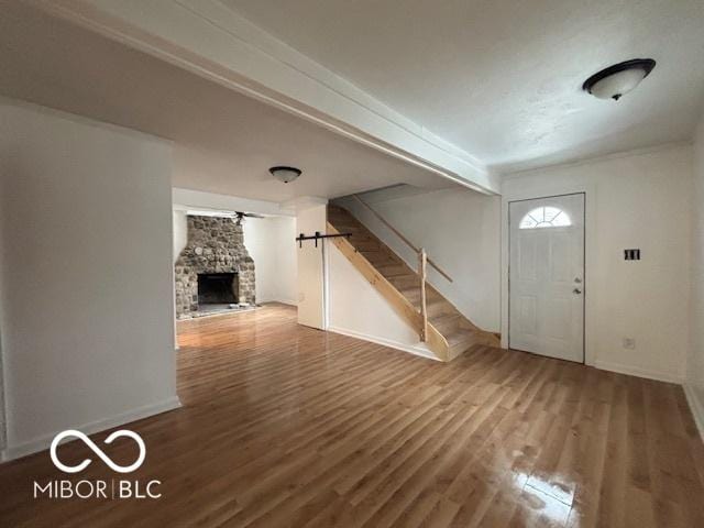 foyer entrance featuring wood-type flooring and a stone fireplace