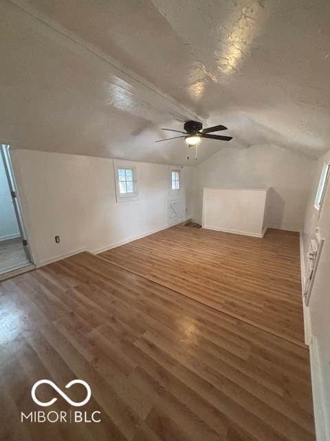 additional living space with lofted ceiling, dark hardwood / wood-style floors, and a textured ceiling