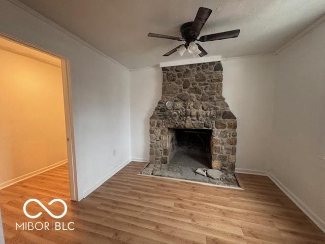 unfurnished living room with crown molding, a stone fireplace, ceiling fan, and hardwood / wood-style flooring