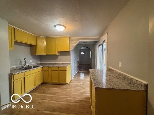 kitchen featuring light stone countertops, sink, light brown cabinets, and light hardwood / wood-style flooring