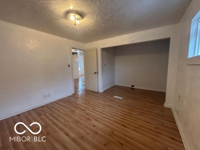 unfurnished bedroom with dark hardwood / wood-style floors and a textured ceiling