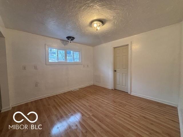 unfurnished room with wood-type flooring and a textured ceiling