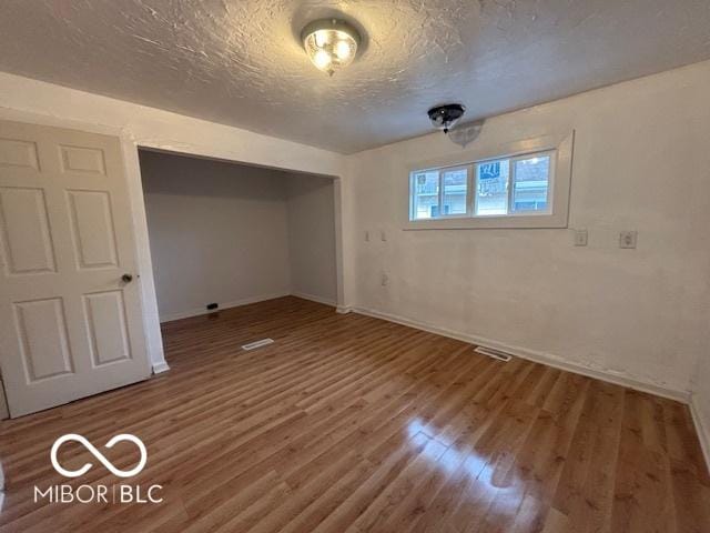 unfurnished bedroom featuring hardwood / wood-style flooring, a textured ceiling, and a closet