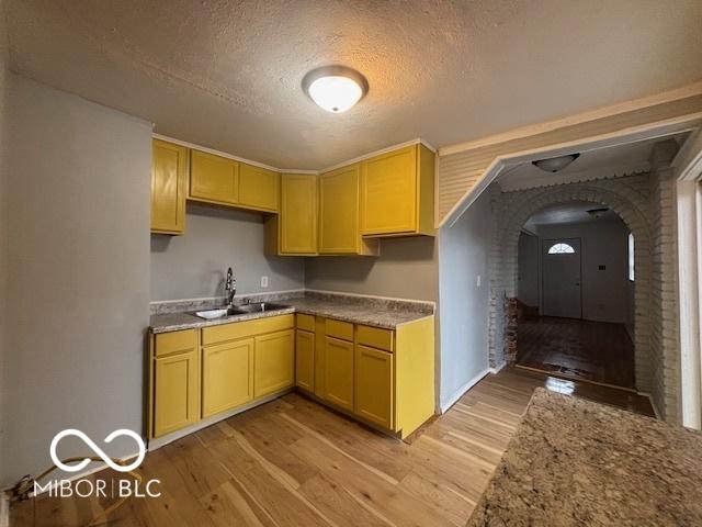 kitchen featuring sink, light brown cabinets, a textured ceiling, and light hardwood / wood-style flooring