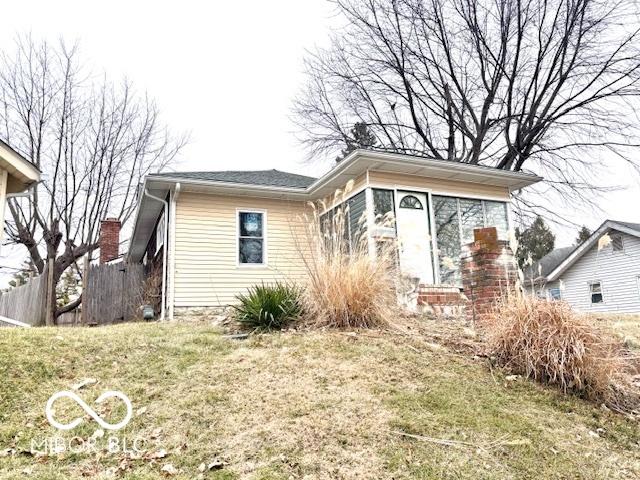 bungalow-style home with fence and a front lawn