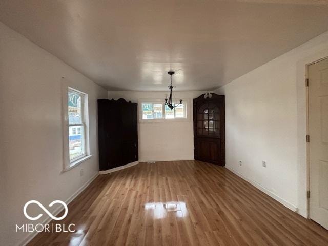 unfurnished dining area featuring hardwood / wood-style floors and an inviting chandelier