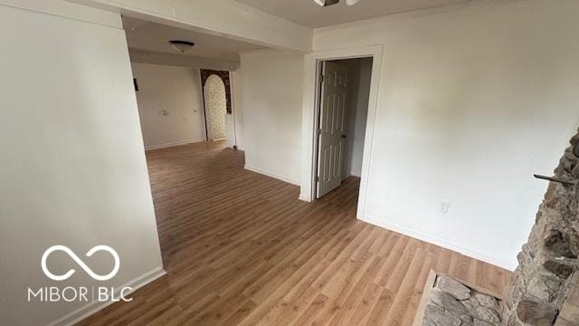 spare room featuring baseboards, ceiling fan, arched walkways, and wood finished floors