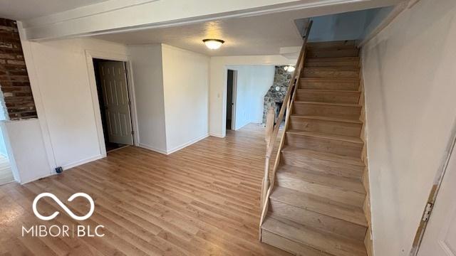 unfurnished room featuring baseboards, stairs, and wood finished floors