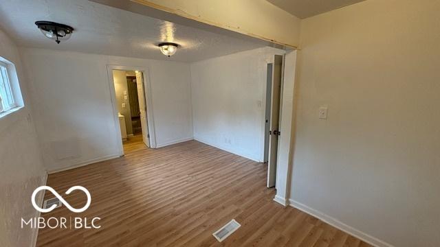 empty room featuring baseboards, wood finished floors, and visible vents