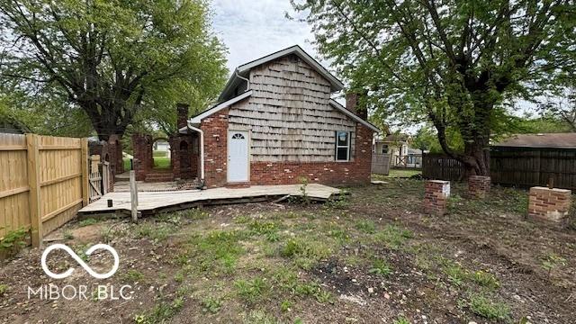 rear view of property featuring brick siding, a fenced backyard, and a wooden deck