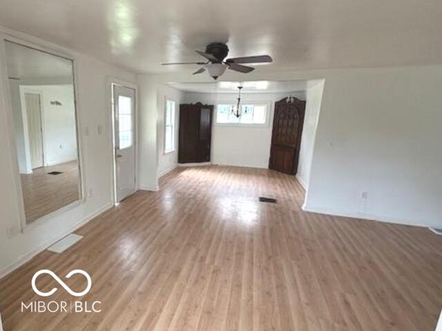 unfurnished living room featuring baseboards, a ceiling fan, and light wood-style flooring