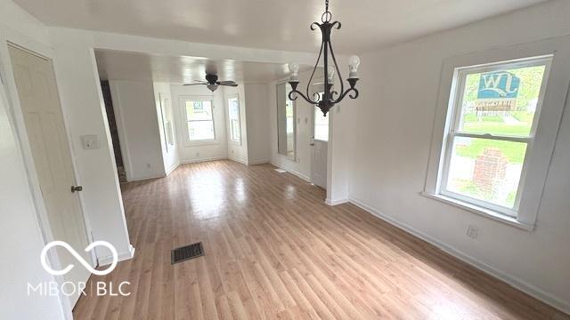 unfurnished dining area featuring light wood-style floors, baseboards, visible vents, and a notable chandelier
