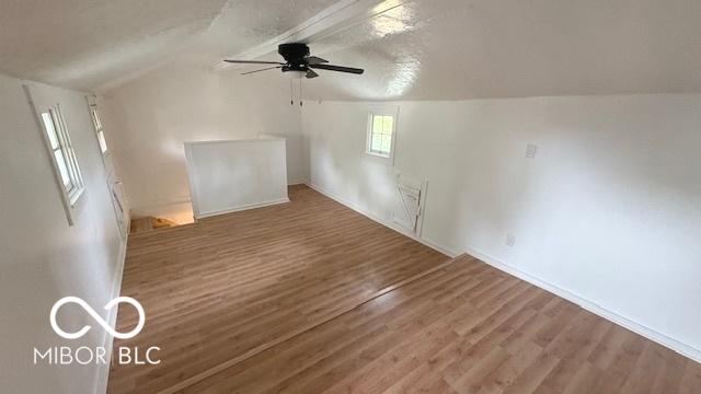 bonus room with wood finished floors, lofted ceiling, baseboards, ceiling fan, and a textured ceiling