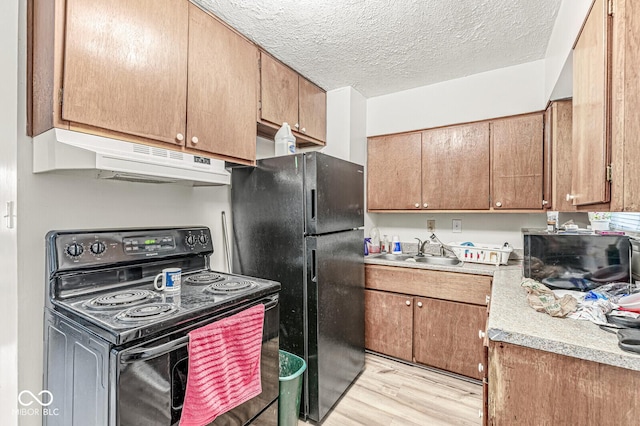 kitchen with light wood-type flooring, sink, a textured ceiling, and black appliances