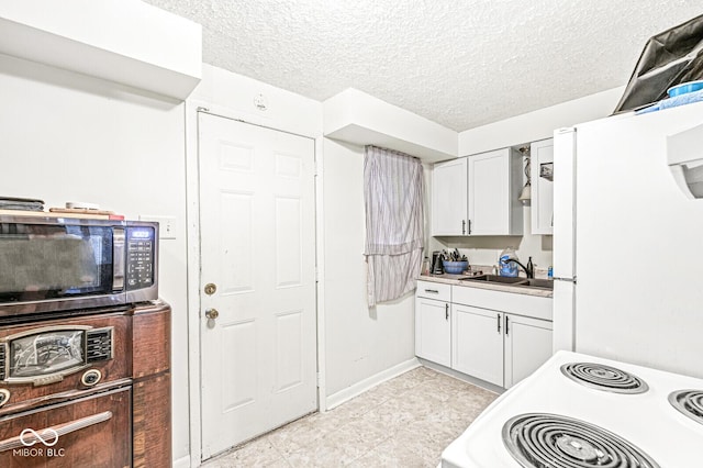 kitchen featuring sink, electric range oven, a textured ceiling, white fridge, and white cabinets